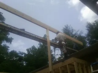 Carpenter setting a ridge beam over a new addition frame — Ice Dam Removal by Roofing Brothers in Loranger