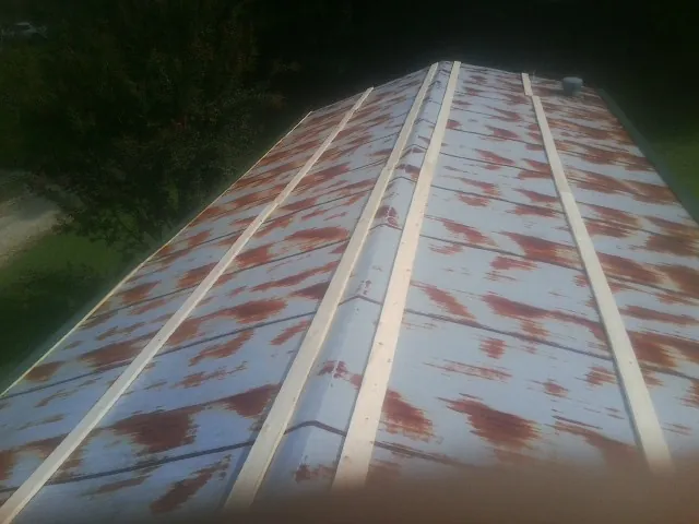 Rusted metal roof panels with new wood purlins before replacement — Storm Damage Roof Repair in Loranger by Roofing Brothers