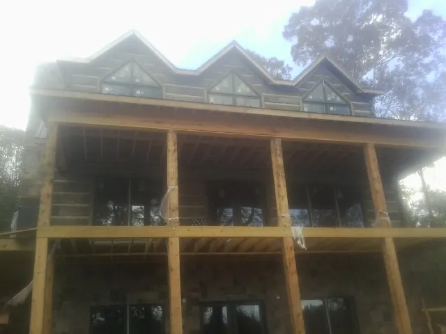 Dormers and porch framing on a large log home under construction — Roof Coating work by our crew in Loranger