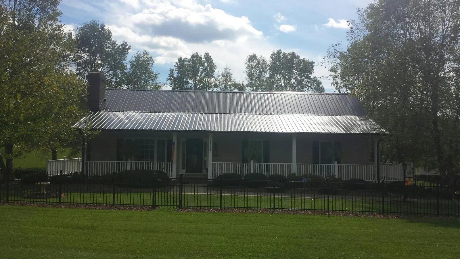 Gray metal roof on a brick ranch with a full width front porch — Gutter Guard Installation work by our crew in Loranger