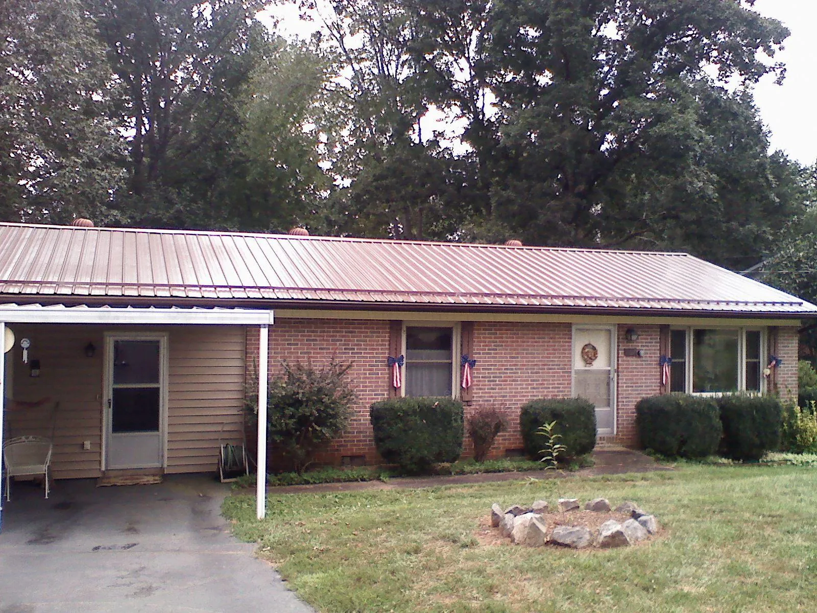 Bronze metal roof and carport on a brick ranch home — Roof Repair work by our crew in Loranger