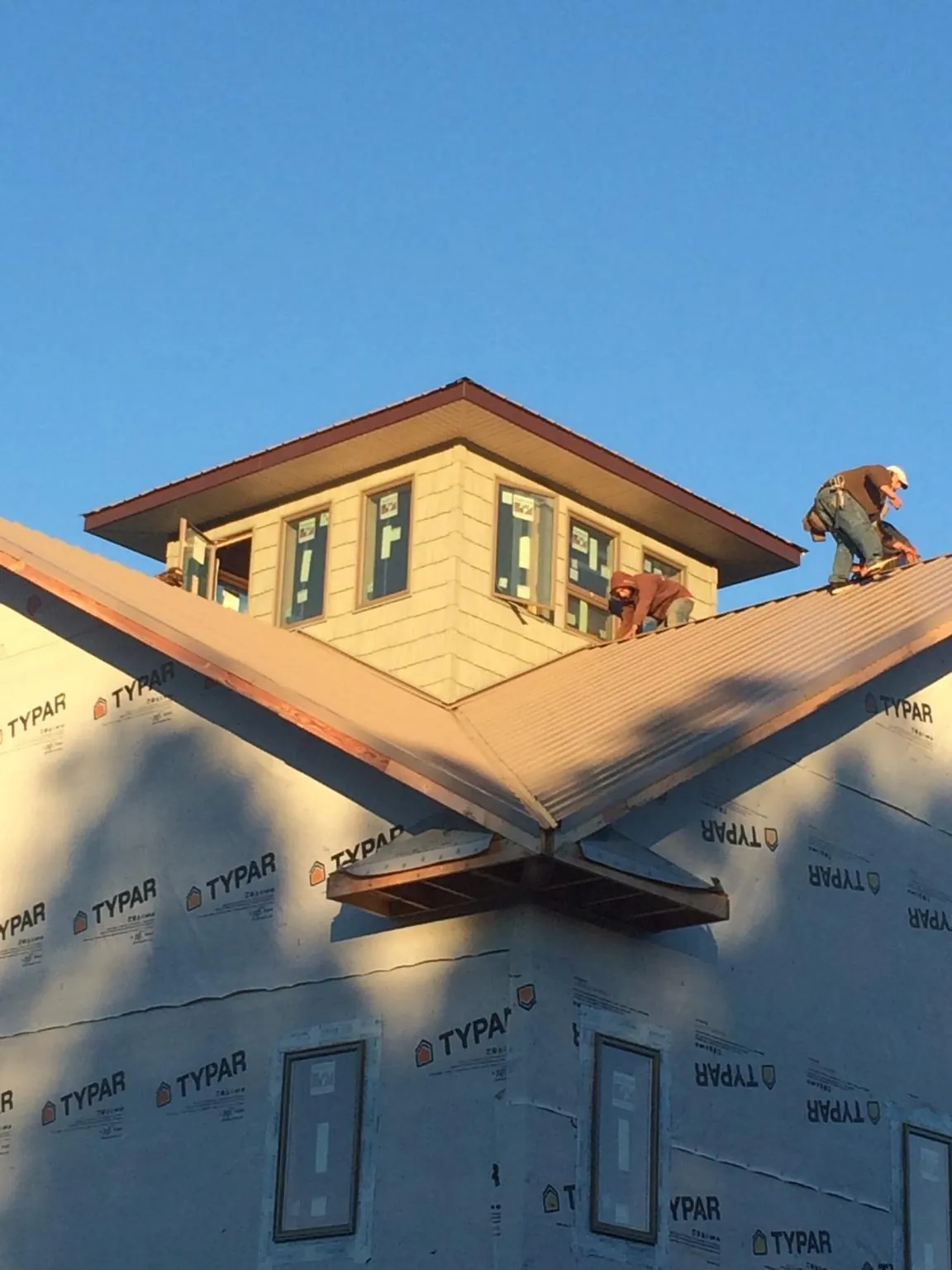 Roofers working around a rooftop cupola on a new metal roof at sunset — Roof Waterproofing in Loranger by Roofing Brothers